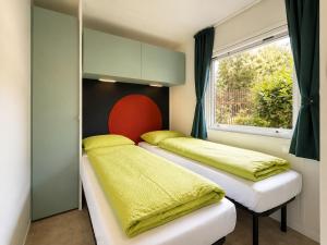 two beds in a room with a window at Camping Al Porto - Mini Glamping & Mobile Homes in Nago-Torbole +22 photos