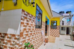 a yellow building with a brick wall at Marindo Lodge Moshi in Moshi