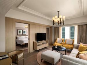 a living room with a couch and a tv and a bed at Pullman Chennai Anna Salai - Premium Brand By Accor in Chennai