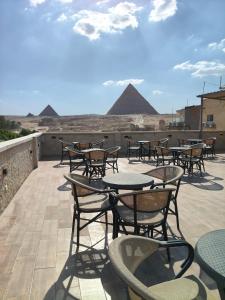 a patio with tables and chairs with pyramids in the background at Giza Pyramids Hotel in Cairo