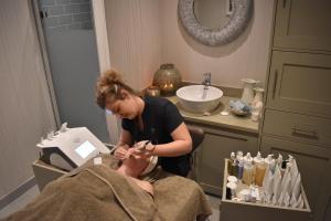 a woman in a bathroom doing a mans hair at Fishmore Hall Hotel and Boutique Spa in Ludlow