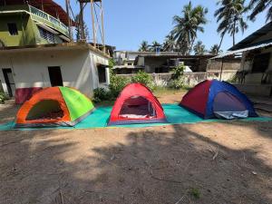 three tents are set up on a dirt field at Sea front tent house in Murud