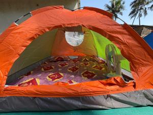 an orange and green tent with a bed in it at Sea front tent house in Murud