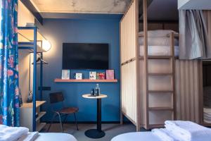a room with two bunk beds with a table and a tv at JOST Hôtel Le Havre Centre Gare in Le Havre +38 photos