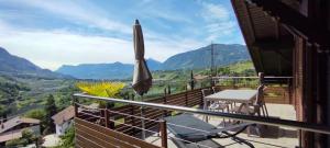a balcony with an umbrella and a table and chairs at Ferienwohnungen Braiter in Rifiano