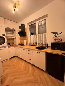 a kitchen with white cabinets and a sink at Aura Home - Livezeni Hiperbara in Livezeni