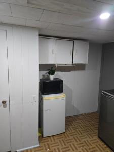 a small kitchen with white cabinets and a microwave at Brossard room 3 in Brossard