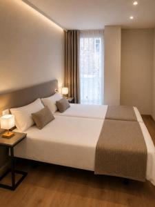 a bedroom with a large white bed and a window at Pensión O Novo in Treacastela