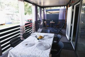 a table and chairs on a screened porch with a table and plates at Mobile Home ADRIA in Privlaka