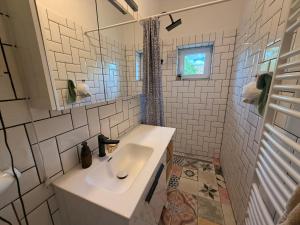 a white bathroom with a sink and a window at Balaton Breeze in Balatonalmádi