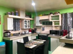 a kitchen with green walls and white cabinets at Maeganbeverly's Place in Santa Fe +5 photos