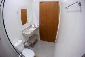 a bathroom with a toilet and a sink and a wooden door at Pousada Vale Verde com café da manhã in Lindóia +31 photos