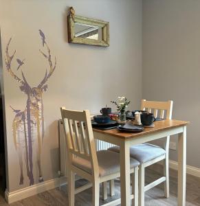 a dining room table with two chairs and a deer on the wall at Craigdarroch Guest House in Contin