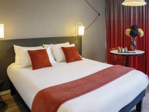 a hotel room with a large bed with red curtains at Ibis Alès Centre Ville in Alès +82 photos