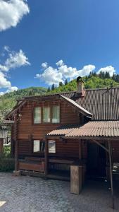 a wooden house with a roof on a brick yard at Pid skeleju in Rakhiv