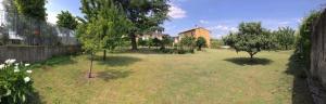 a yard with trees and a building in the background at La Rosa Garden in Campi Bisenzio