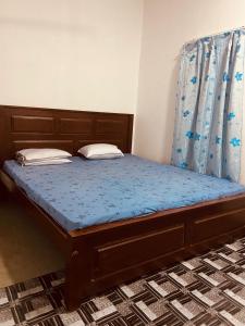a bed with a wooden frame and blue sheets and pillows at KR Villa in Arugam Bay