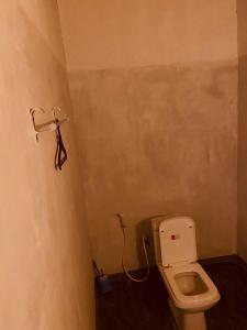 a bathroom with a toilet and a hanger on the wall at KR Villa in Arugam Bay