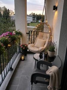 a swinging chair on a balcony with flowers at Lenka Lux Apartmans in Divčibare
