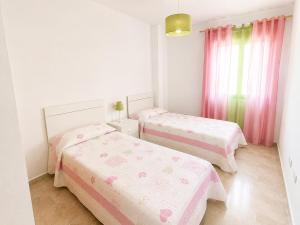 a bedroom with two beds and pink curtains at LyriosHomes Beach Costa Ballena in Chipiona