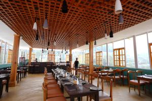 a dining room with tables and chairs and windows at Nagarkot Zip Coaster Pvt Ltd in Nagarkot