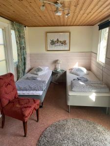 a room with two beds and a red chair at Örkelljunga cottage in Orkelljunga