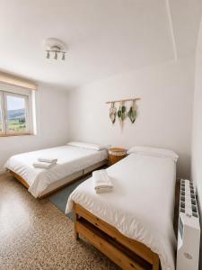 two beds in a room with white walls and a window at Fantastico retiro rural en el corazon de Euskadi in Elgóibar