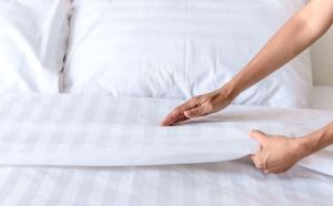 a person putting a white sheet on a bed at Mayflower Motel Milford in Milford +4 photos