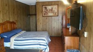 a bedroom with a bed and a flat screen tv at Mayflower Motel Milford in Milford