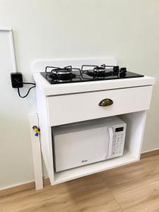 a white stove top oven sitting next to a microwave at ApartPousada Residencial dos Reis in São Francisco do Sul +35 photos