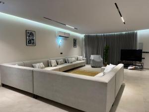 a living room with a large couch and a television at شاليه مرزوقة in Buraydah