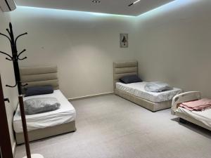 two twin beds in a room with a blue light at شاليه مرزوقة in Buraydah