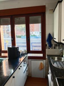 a kitchen with a sink and two windows at Bilbao Room 001 in Bilbao +1 photo