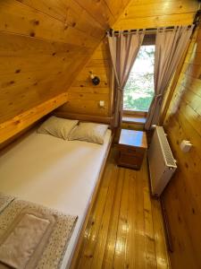 a bedroom with a bed in a wooden cabin at Apartman Tri srca Zlatar in Nova Varoš