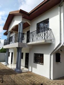 a white house with a balcony and a porch at Manoir des Princesses in Yaoundé