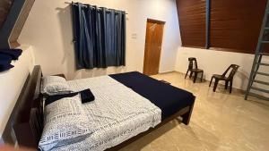 a bedroom with a bed and two chairs in it at Aastha Gokarna in Gokarn