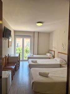 a hotel room with four beds and a television at Hostal Lizana 2 in Huesca