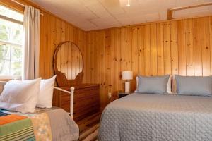 a bedroom with wooden walls and two beds and a window at Beach Boats Beds in Sneads Ferry