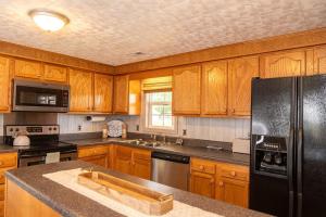 a kitchen with wooden cabinets and a black refrigerator at Beach Boats Beds in Sneads Ferry