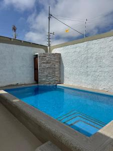a large blue swimming pool next to a white wall at Casa Privada con Piscina in Salinas