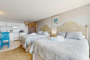 two beds in a hotel room with a kitchen at Oceanfront suite with bay views full kitchen balcony AC & firepit in North Truro