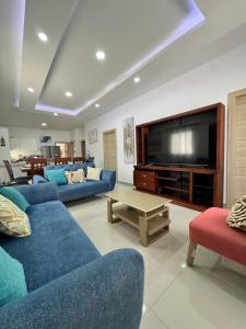 a living room with blue couches and a flat screen tv at Casa Privada con Piscina in Salinas