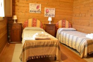 two beds in a room with wooden walls at Il Giardino Del Sole in Agnone Bagni