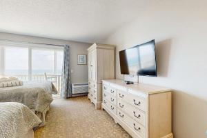a bedroom with two beds and a television on a dresser at Oceanfront getaway with Bay-view balcony full kitchen AC in North Truro