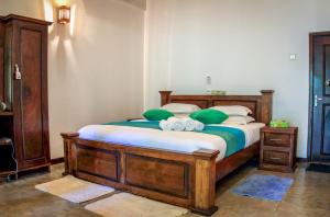 Un dormitorio con una gran cama de madera con almohadas verdes en The Green Edge, en Dambulla