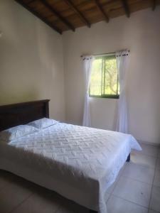 a bedroom with a white bed and a window at El Renacer in San Gil