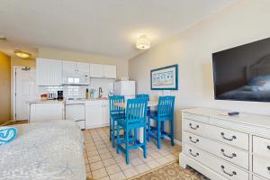 a bedroom with a kitchen with blue chairs and a bed at Oceanfront hideaway with full kitchen AC sunrise-view balcony in North Truro