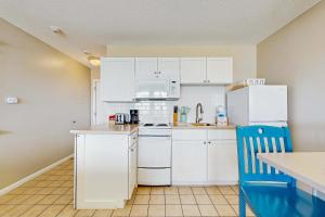 a kitchen with white appliances and a blue chair at Oceanfront hideaway with full kitchen AC sunrise-view balcony in North Truro