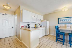 a kitchen with white cabinets and a white refrigerator at Oceanfront hideaway with full kitchen AC sunrise-view balcony in North Truro +18 photos
