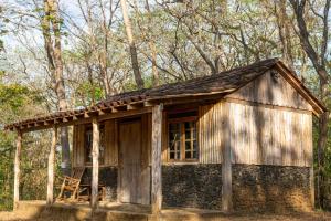 a small wooden cabin in the woods with a chair at Hostal Flor de Pochote in Masatepe